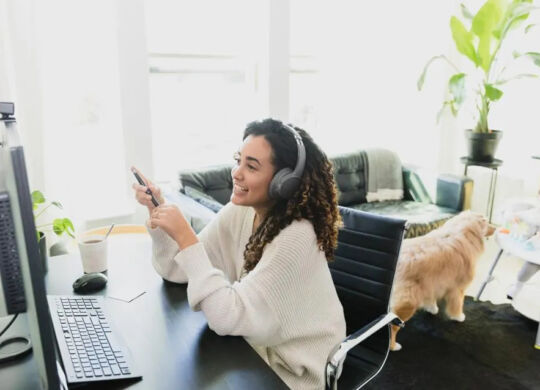Remote work employee on conference call while child and pet play in background.