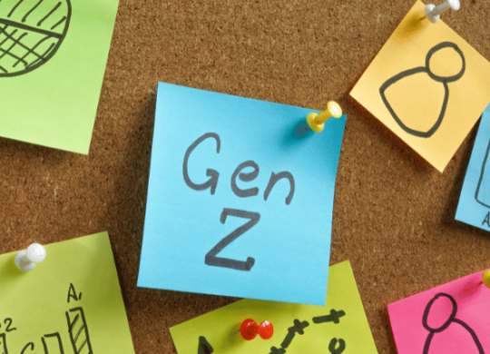 "Gen Z" written on a sticky note placed on a cork board. It is surrounded by additional sticky notes.