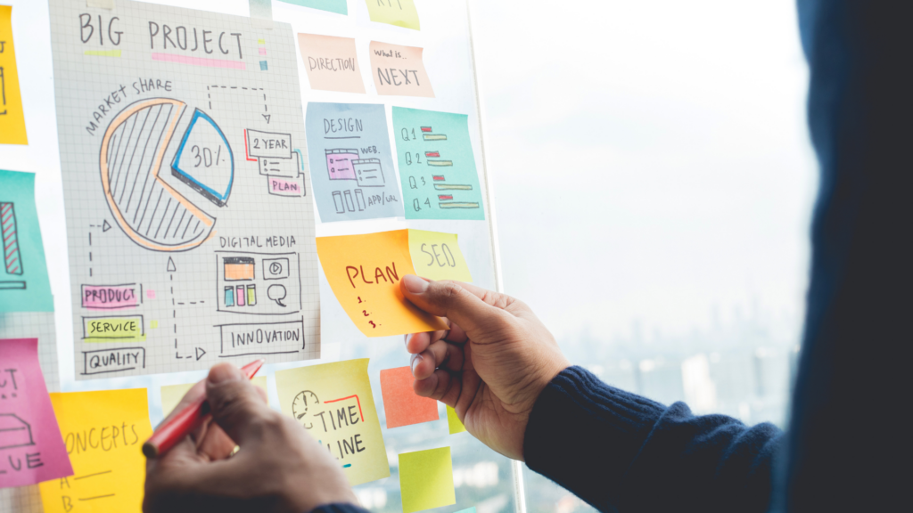 Man working on a marketing for small business strategy using a planning board filled with handwritten notes, diagrams, and papers to organize ideas and business goals.